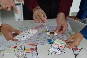 Creative Teamwork in UX UI Design. Designers engaging in a lively discussion over digital prototypes and sketches. photo