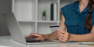 E-commerce and Credit Card Usage. Person interacting with a laptop and holding a credit card for online transactions at a modern desk. photo