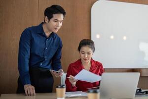 Analysis and Data Presentation. A man and woman assess financial documents in an office workspace. photo