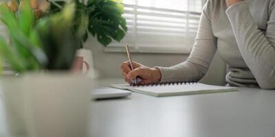 Concentration and Writing. Close-up of a person writing in a notebook while working at a desk. photo