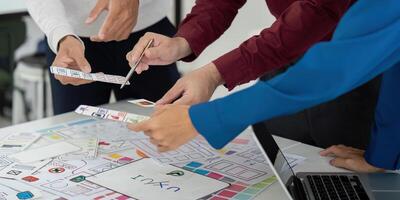 Collaboration and UX Design. Team members engaged in a collaborative UX design meeting, analyzing prototypes and sketching ideas together. photo