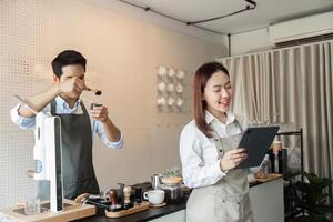 Barista Craftsmanship and Technology. A skilled barista prepares coffee while another reviews orders on a tablet. photo