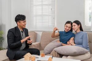 Successful Real Estate Meeting. A real estate agent discusses property keys with two satisfied clients. photo