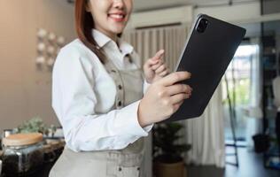 Digital Management in Coffee Shops. A barista interacts with a tablet, enhancing customer experience. photo