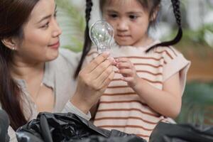 Learning About Sustainability and Recycling. A mother explains the recycling process using a light bulb in their eco-friendly project. photo