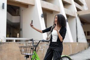 Selfie and Outdoor Enjoyment. A woman takes a fun selfie with her bicycle, capturing a moment of joy while navigating urban spaces. photo