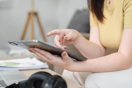 Digital Tools and Efficiency. A woman interacts with a tablet to manage tasks effectively while working from home. photo