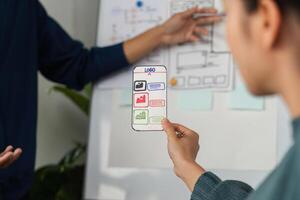 Design Collaboration and Creative Development. A team member presents a mobile app prototype to colleagues. photo