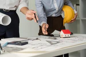Project Collaboration and Architectural Planning. Professionals strategizing over architectural designs with tools and a model house. photo