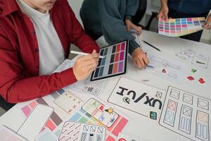 Creative Collaboration and Design Prototyping. Team members engaged in a lively session, refining design ideas using digital tools and paper prototypes. photo