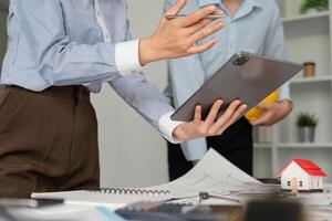Design Discussions and Digital Tools. A professional presenting plans on a tablet during a team meeting. photo