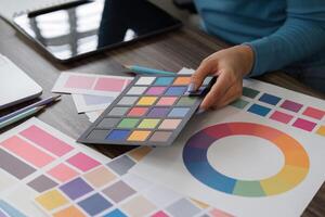 Color Selection and Artistic Design. A hand selecting color swatches for a creative project on a wooden workspace. photo