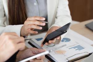 Smartphone Communication and Data Sharing. Close-up view of professionals exchanging information through devices during a meeting. photo