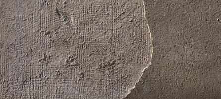 An old concrete wall shows a textured surface with a rough edge and a smooth area. photo