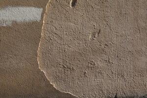 A textured wall with layers of beige plaster creates a weathered and vintage feel, perfect for backgrounds. photo