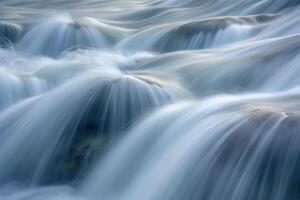 Flowing water cascades gently over smooth rocks in a tranquil river setting photo