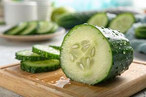 Fresh cucumber sliced on a wooden cutting board with droplets of water in a kitchen setting photo