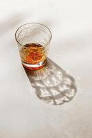 Crystal Whiskey Glass with palm leaf shadow and sunlight reflection on beige background, neutral photo minimal style, aesthetic summer still life, refraction at shine alcohol drink, caustics