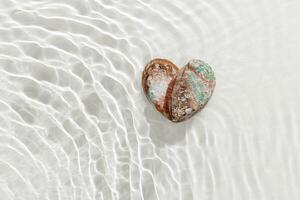 Shiny Shells of abalone as heart with waves sea water textured background, closeup seashell with pearlescent iridescent surface, color clamshell Haliotis, top view, sea oceanic nature love concept photo