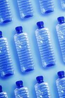 Pattern from Clear plastic water bottles with blue cap on light blue background with soft shadow, Minimal top view, themes of ecology, recycling, sustainable living, reduce disposable plastics photo