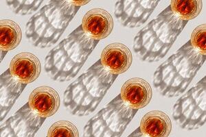 Transparent alcohol Glasses with dark shadows at sunlight on beige table, creative linear dynamic pattern, top view minimal style, aesthetic flat lay shiny glass at natural light, summer drink photo