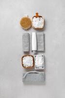 Spa, wellness, bath products as minimal aesthetic pattern, magnesium salt flakes, folded grey towels, natural brushes, massagers, reusable pads, gray background, top view lifestyle content photo