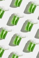 Transparent Pump dispensers with green colored liquid as pattern. Skincare essentials, spa beauty products on light background, Cosmetic bottles at sunlight, minimal top view geometric lauout photo