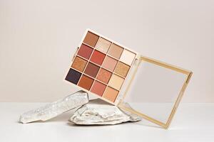 Eyeshadows palette mockup on stand from natural stone. Beauty product cosmetic powder for make up eye, beige brown color scheme, matte and shimmer tints. Cosmetic product minimal style. photo