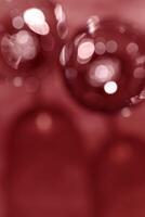 Glasses of Red wine as blur background, abstract backdrop red wine colored, natural light and dark shadow, glare and shining bokeh texture, maroon color aesthetic wallpaper. Holiday concept photo
