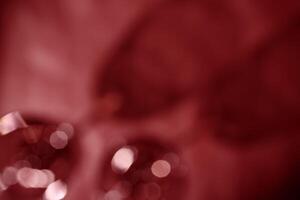 Glasses of Red wine as blurred background, abstract backdrop red wine colored, natural light and dark shadow, glare and shining bokeh texture, maroon color aesthetics wallpaper. Holiday concept photo