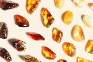 Amber stones at sunlight on beige background, minimal style pattern from transparent stones in line, color gradient. Natural gemstone mineral, healing crystal. Top view Amber Nature gems photo