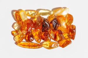 Natural gemstone amber stones at sunlight, yellow orange gradient color isolated white background. Natural mineral. Aesthetic lifestyle Amber gems, flatlay pattern, pieces ancient resin photo