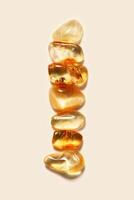 Aesthetic minimal pattern, set of amber stones gradient color on beige background. Line composition from natural gemstones. Summer concept of harmony, spa. Top view, flat lay. Still life photo