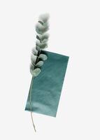Teal color envelope, blank paper card mock-up and branches eucalyptus leaves on white background. Empty colored invitation on table. Minimal modern lifestyle photo. Flat lay, top view, copyspace photo
