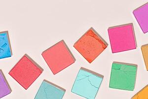 Multi-colored square swatches eyeshadows for makeup on beige background, trend pastel vivid colors textures powder for eye cosmetics, eyeshadow color palette, top view, close up pattern photo