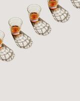 Crystal Whiskey Glasses at row with shadow and sunlight reflection on beige background, minimal neutral pattern, aesthetic top view summer still life, refraction at shine alcohol drink, caustic photo
