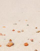 Natural stones amber yellow colored on beige sand. Aesthetic minimal nature scene with pebble stones on fine sandy background. Summer vacation or relaxation concept, selective focus. photo