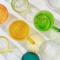 Colored shiny drink Glasses still life with shadow and sunlight reflections on white, minimal aesthetic top view summer photo, refraction at glass cups with sun flare, creative food pattern photo