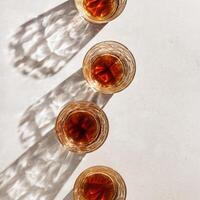 Crystal Whiskey Glasses with shadows at sunlight on beige textured background, minimal aesthetic top view sparkling glasses, sun flare, stong alcohol drink concept, summer still life top view, flatly photo