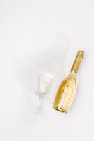 Top view white sparkling wine bottle and glasses wine with sun shadow and flare on light white background. Minimal aesthetic flat lay, golden champagne bottle. Summer alcohol drink concept photo