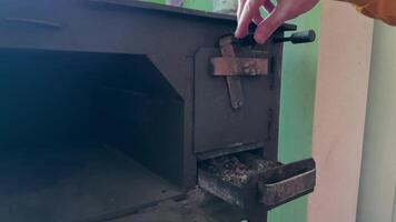 Hand closes the door of wood burning stove after adding logs for warmth. The rustic setup highlights the traditional method of heating, showcasing the cozy atmosphere it creates video