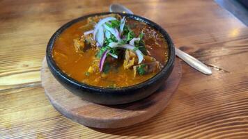 Slow motion view of Ostri, traditional Georgian stew served in rustic clay bowl. Bubbling dish is garnished with fresh herbs and onions, emphasizing its authentic appeal. Bowling Ostri from stove video