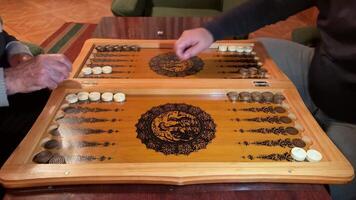 Board game for the older generation. Strategic board game wooden backgammon. Old people throw the dice and make their move in backgammon. Ancient board game for fun video