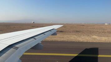 View from window of commercial jet as it moves toward runway. Moving through airport on plane ready for takeoff. View from the window of plane wing bending as it moves along ground. video