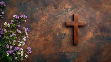 A wooden cross on a rustic background with purple flowers photo
