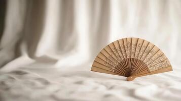 Elegant Bamboo Hand Fan with Floral Design Resting on Soft Fabric A Perfect Summer Accessory photo