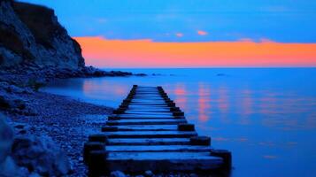 Serene Sunset Seascape Wooden Dock Leading to Calm Ocean Waters Peaceful Evening Coastal Scene with Rocky Shoreline photo