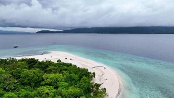 Drone view of a small island with dense tropical trees, pristine white beaches, and stunning blue waters in the Philippines. video