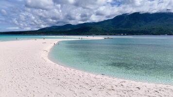 Picturesque drone view of a pristine sandbar island with white sand and volcanic island backdrop in the Philippines. video