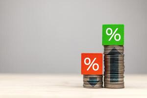 Percent icons in a wooden block on stack of coins with arrows up, and down. interest rate change, percentage rate is falling and rising. business concept with copy space photo